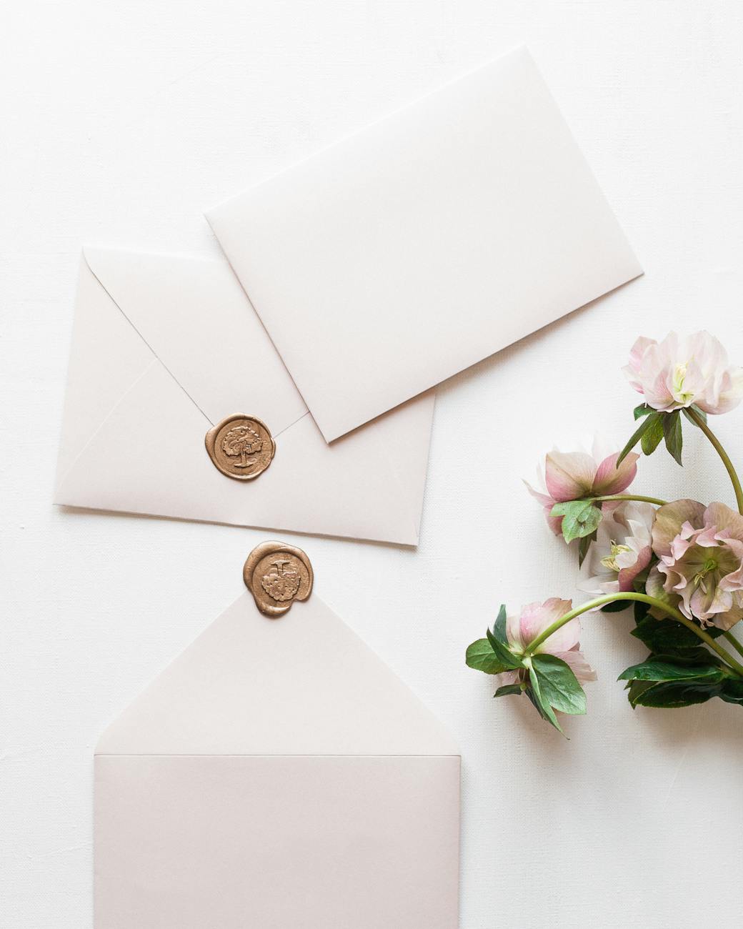 three white envelopes and bunch of pink flowers