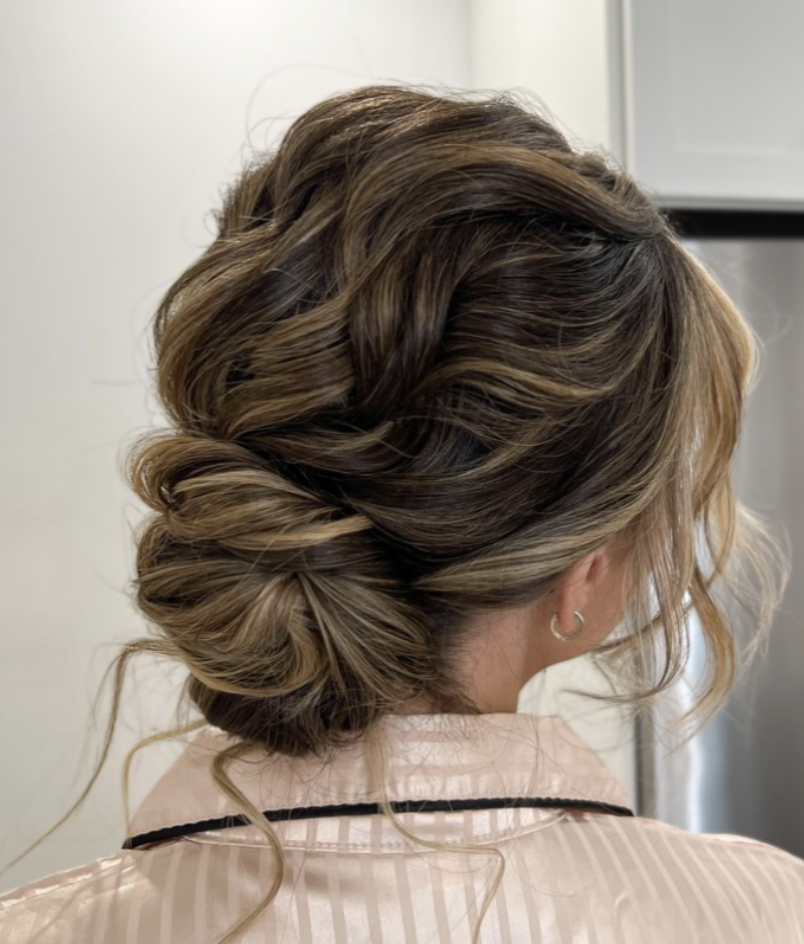 Effortlessly chic boho low bun hairstyle, styled with a relaxed, messy texture by the talented Erika Taft Bridal perfect for the free-spirited bride seeking effortless elegance on her special day.