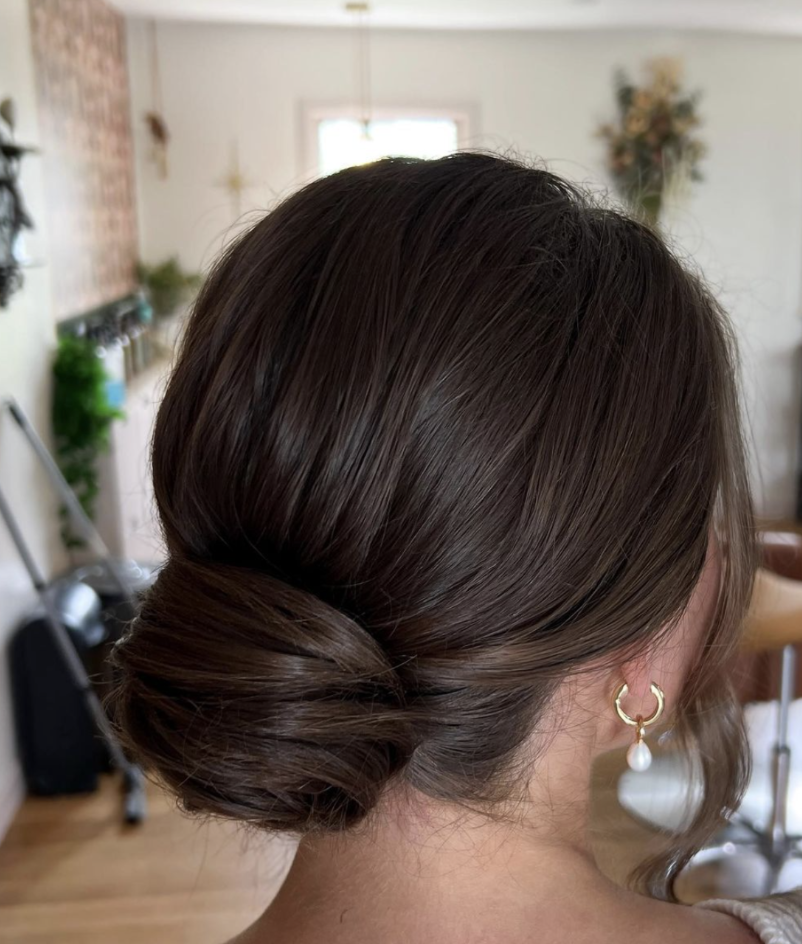 Bride with a beautifully styled low bun hairstyle by Erika Taft Bridal, perfect for a classic and elegant wedding look.