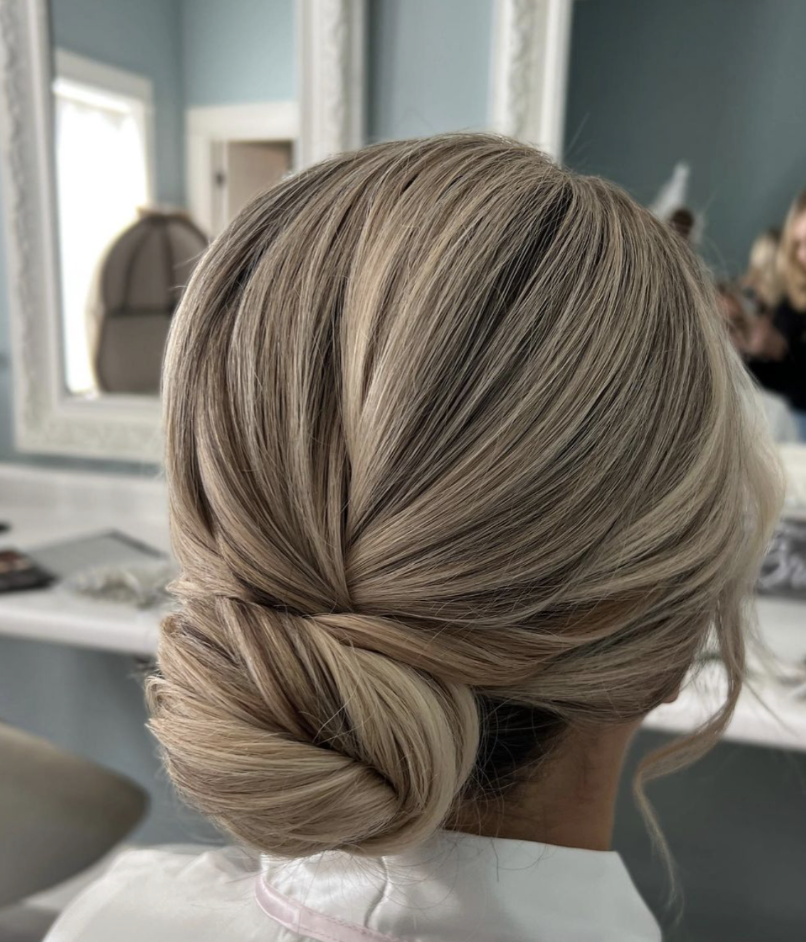 Bride with a beautifully styled low bun hairstyle by Erika Taft Bridal, perfect for a classic and elegant wedding look.