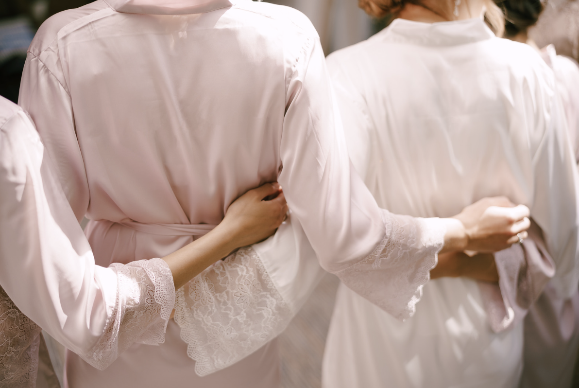Bridesmaids in matching robes, sharing a joyful moment on the wedding day.